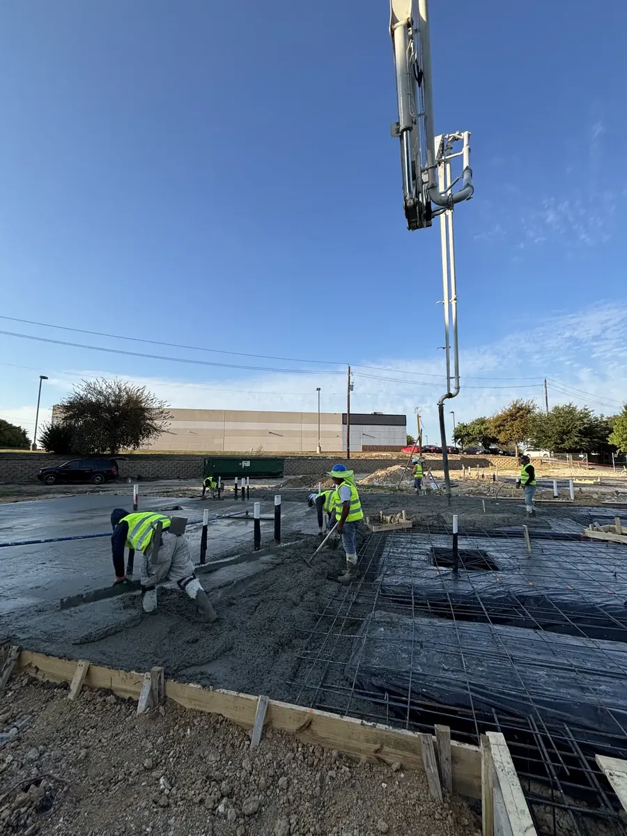 Crew placing concrete over a rebar mat as the pump hose feeds the pour