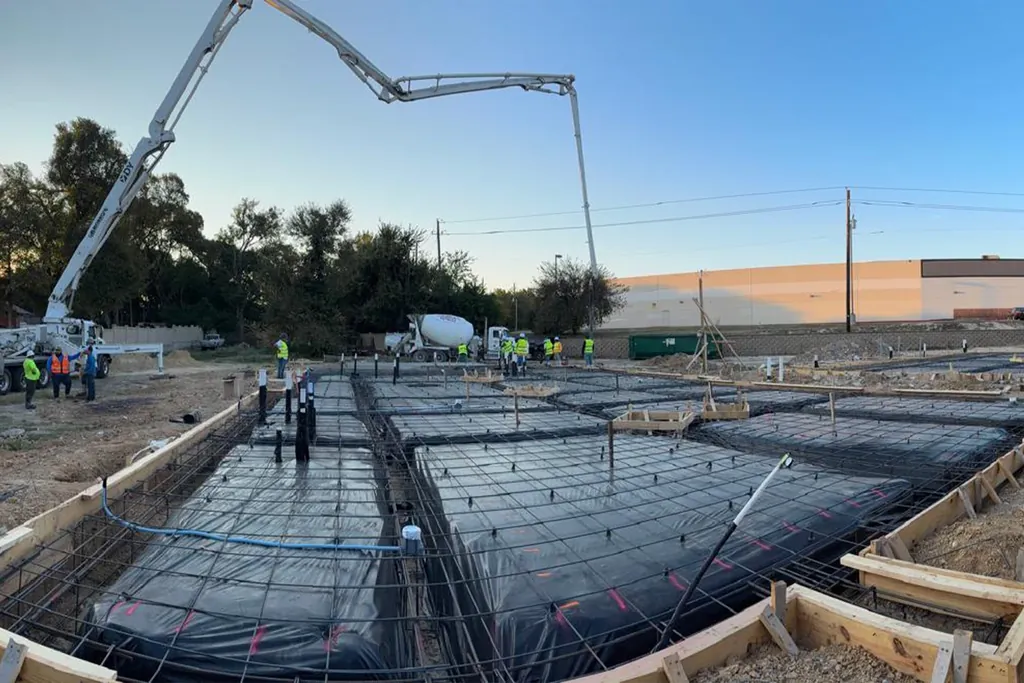 Rebar mats and form boards set for commercial slabs with a pump boom overhead